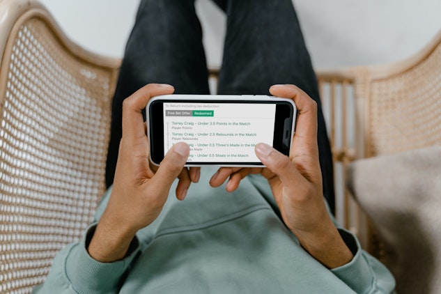 iPhone 11 in the hands of a man using the bet365 bet builder on his phone